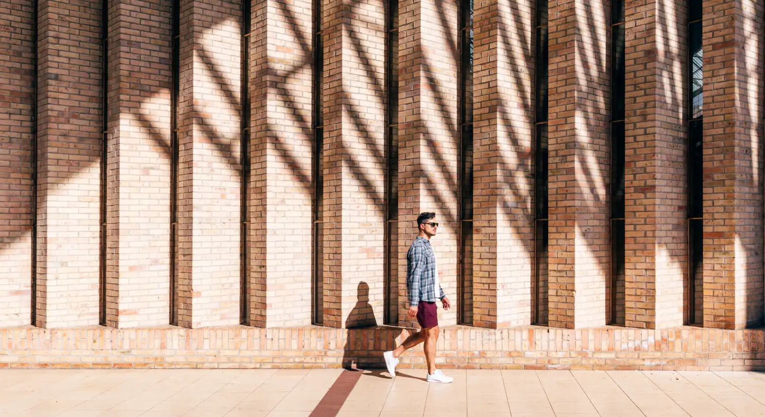 Man walking by brick wall outdoors 