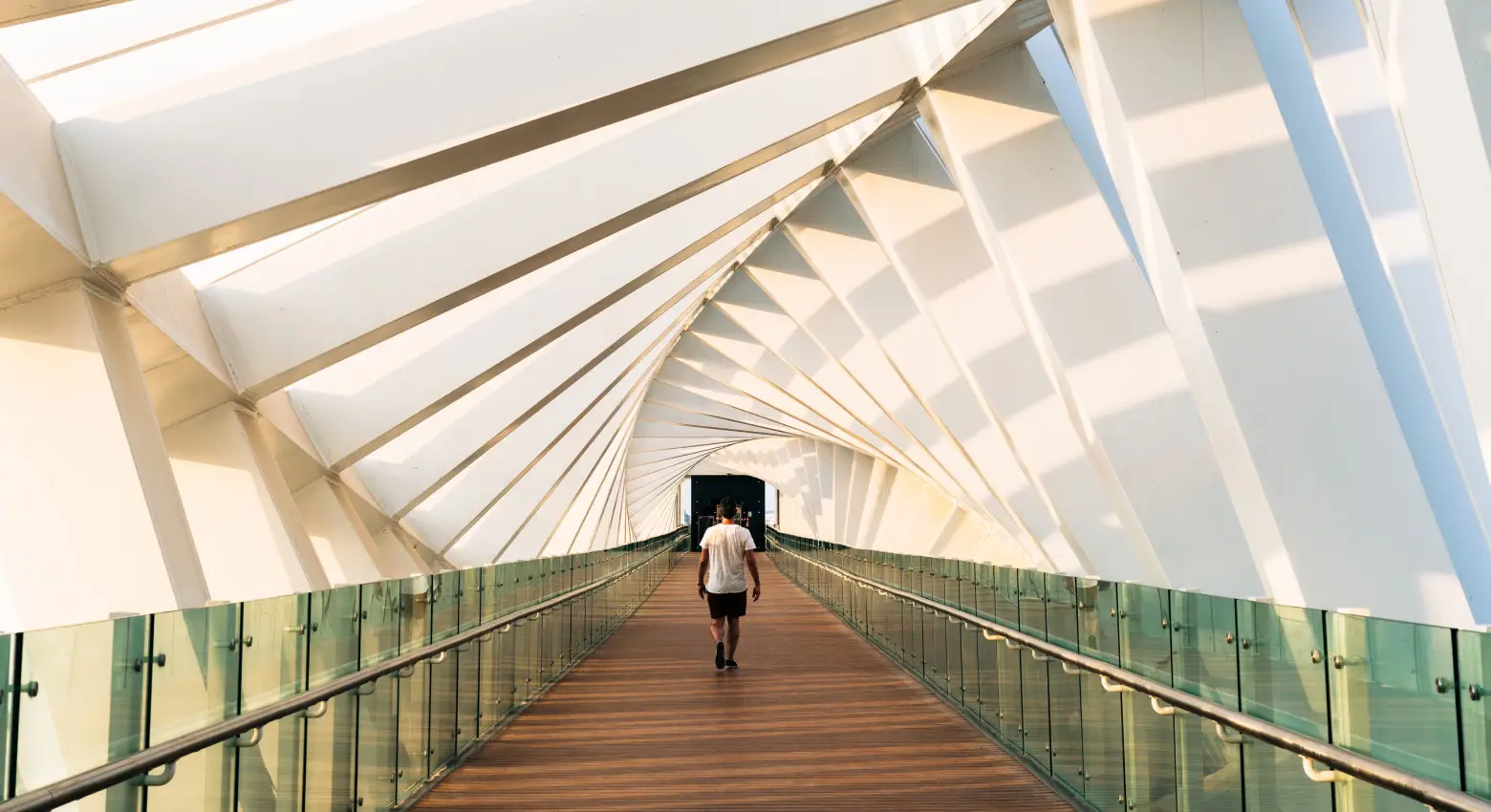 Person walking on bridge between modern architecture 