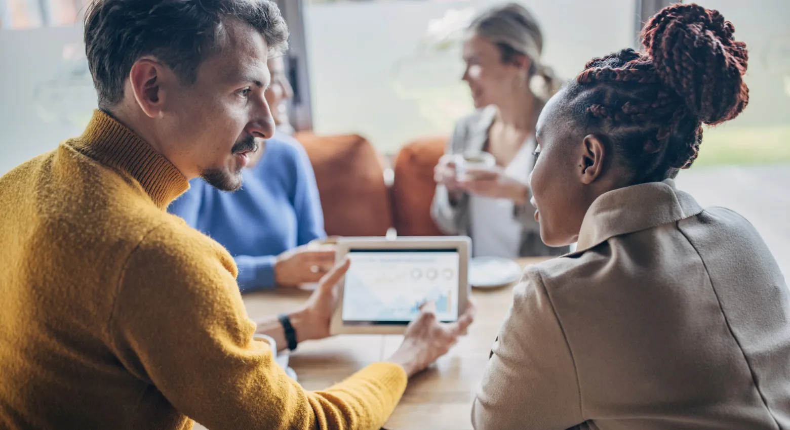 people sharing table with tablet