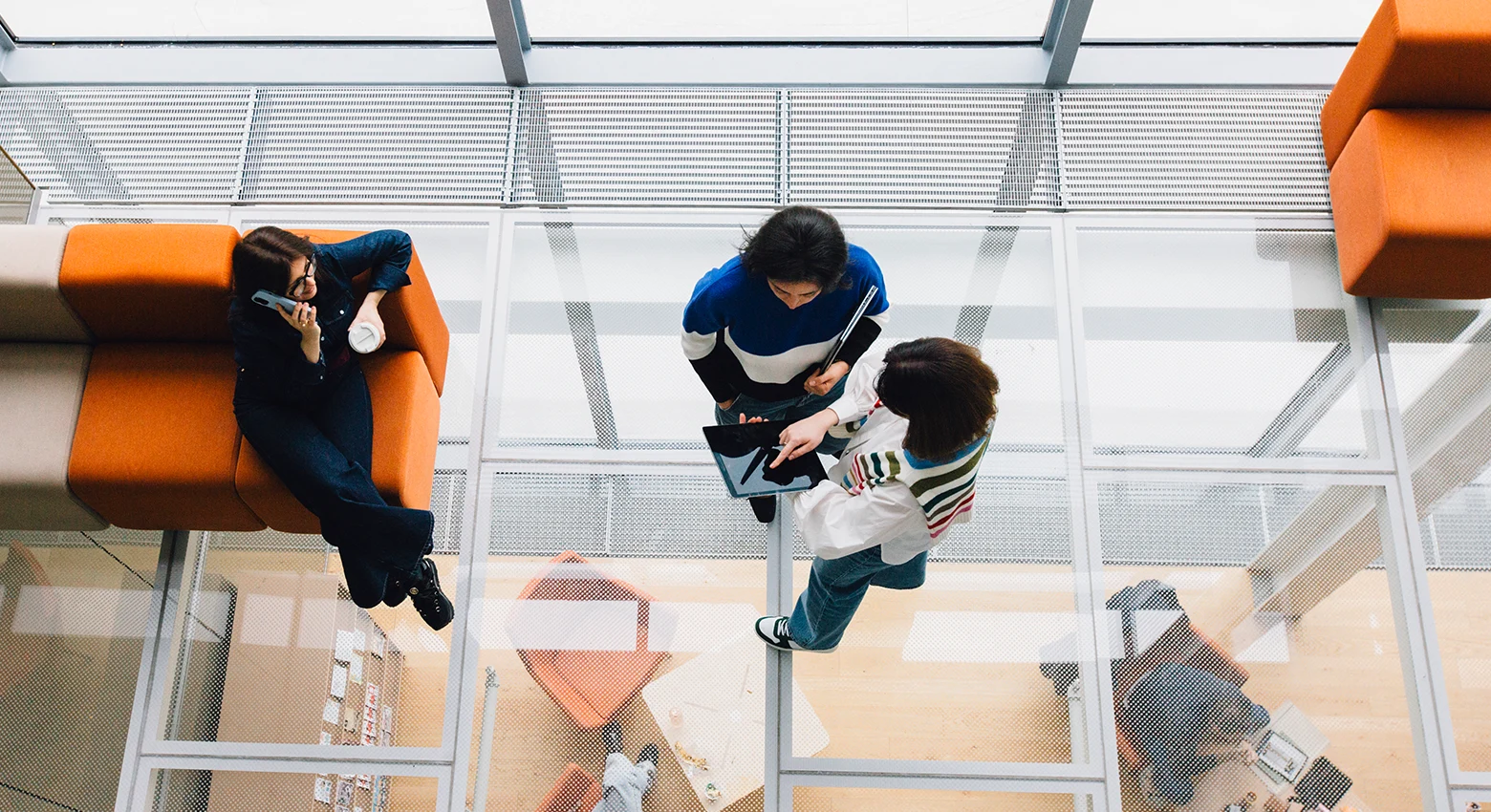 A overhead shot of three engaged people in an office space.