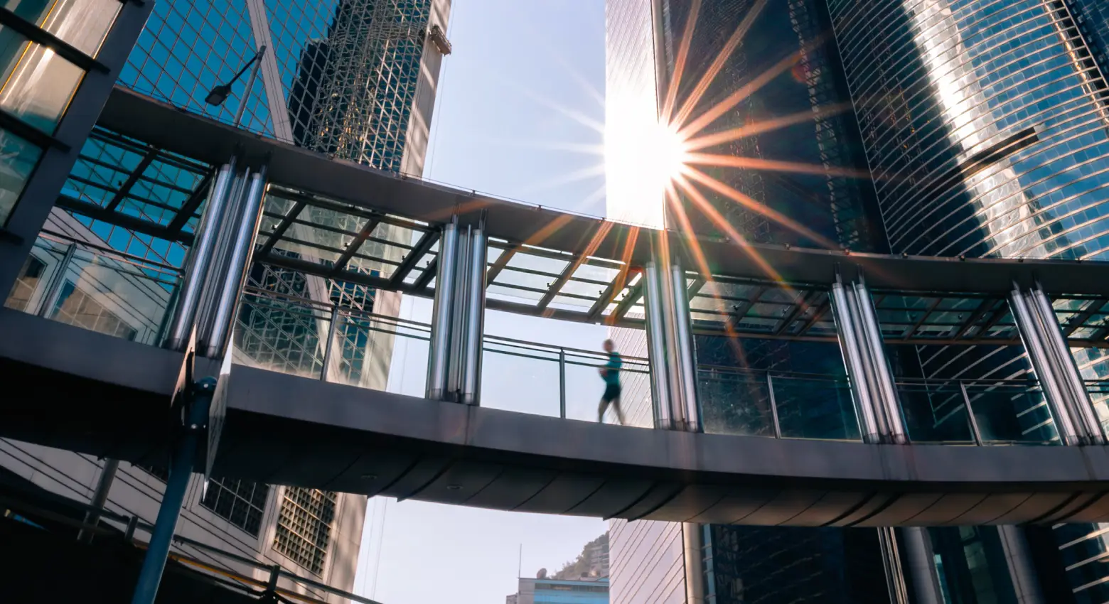 Person walking on bridge between modern architecture 