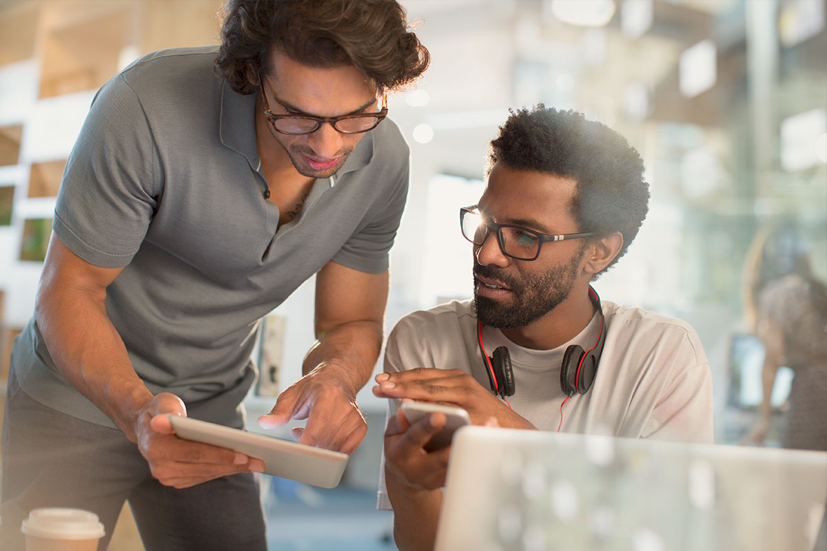 Two men working across devices