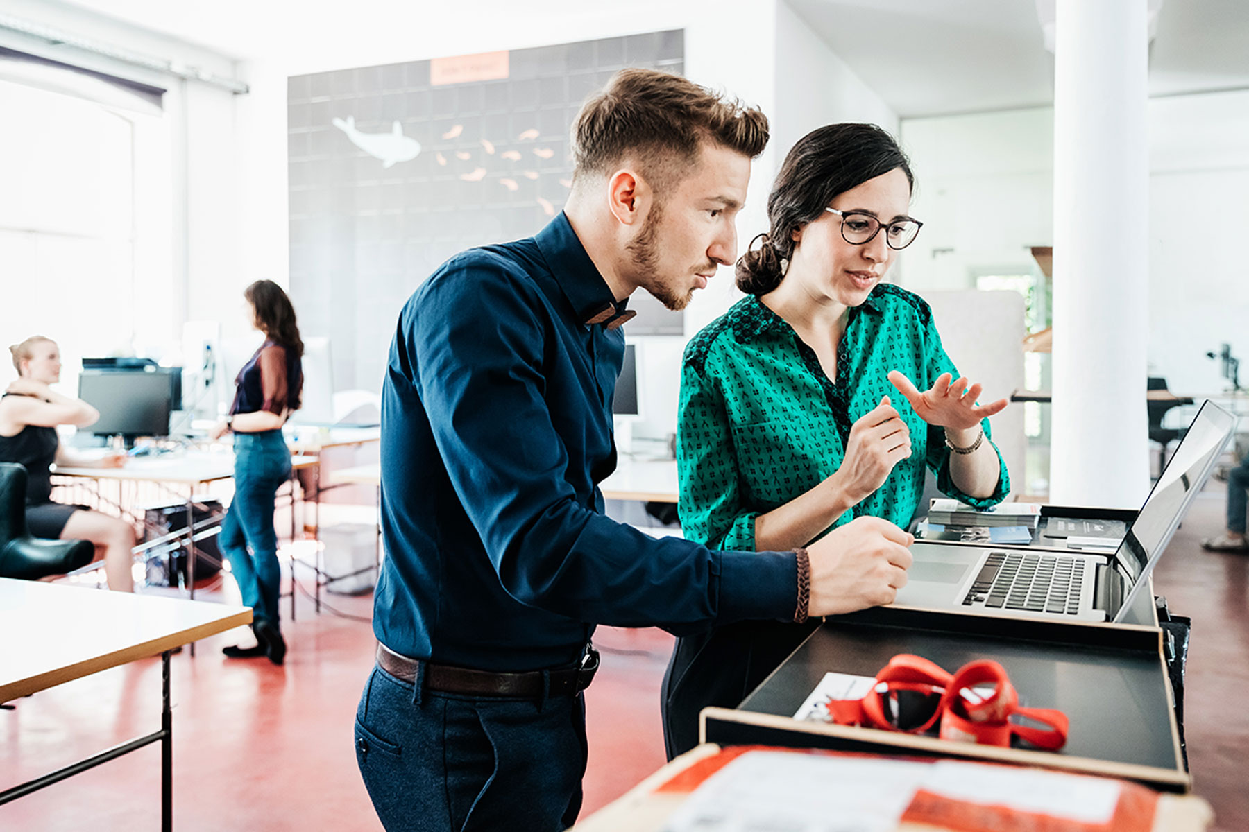 A woman and man employees discussing privacy while looking at a laptop.