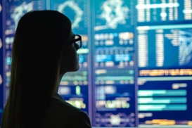 Thumbnail of woman in glasses looking at a computer screen of dashboards