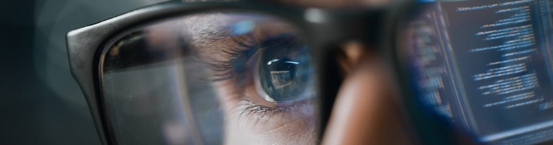 close up of a person's glasses reflecting a screen of code