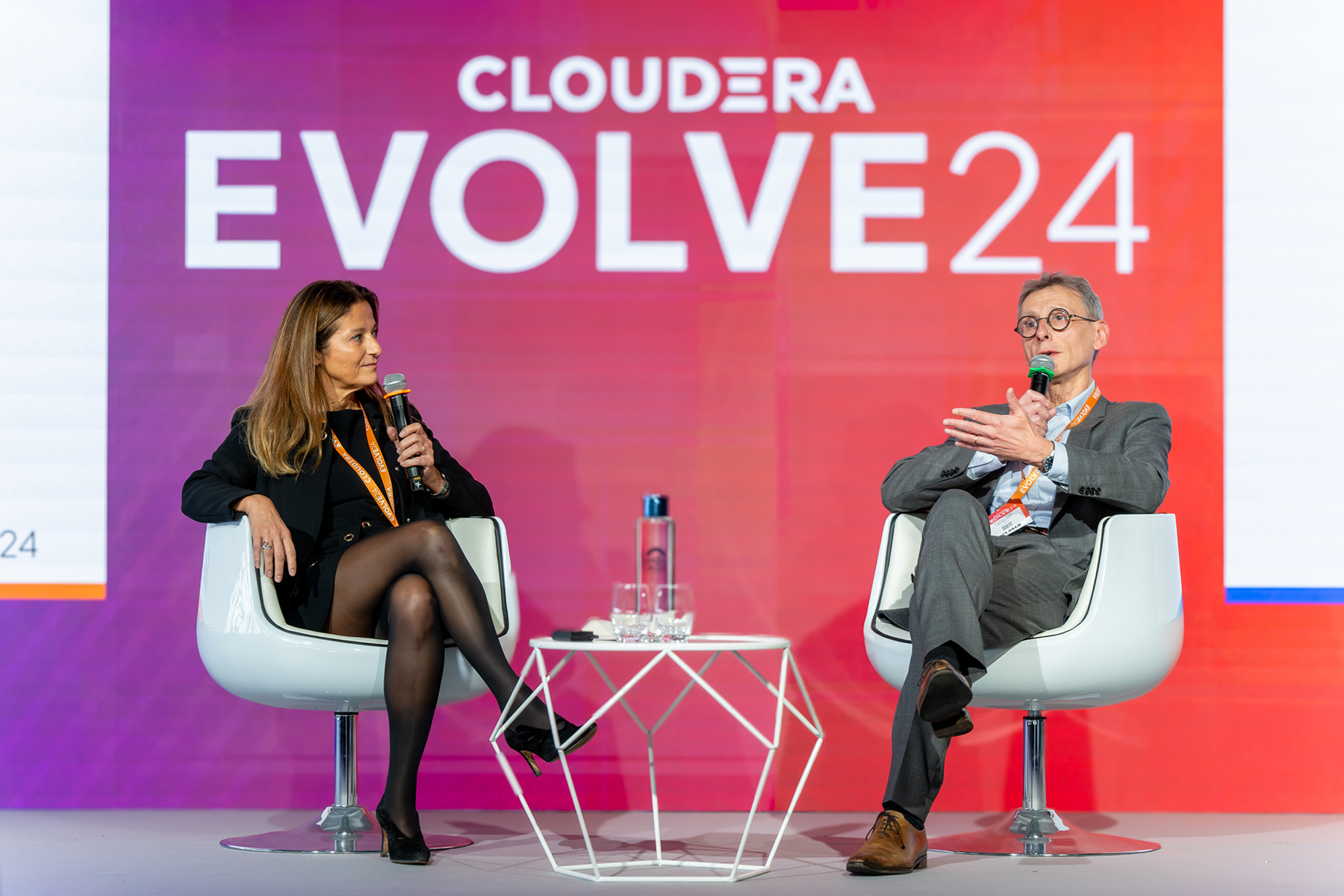 A woman and a man speaking about customer successes on stage