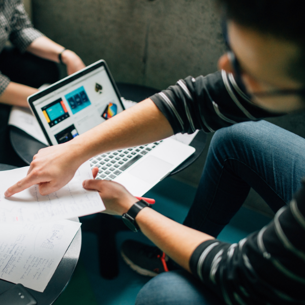 Men looking at laptop and pointing at papaer