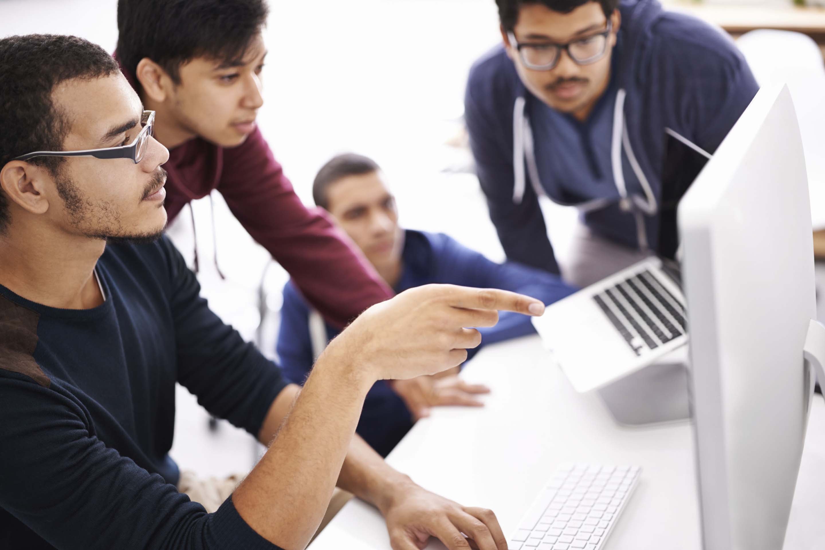 Group of colleagues looking and pointing at the screen of a desktop