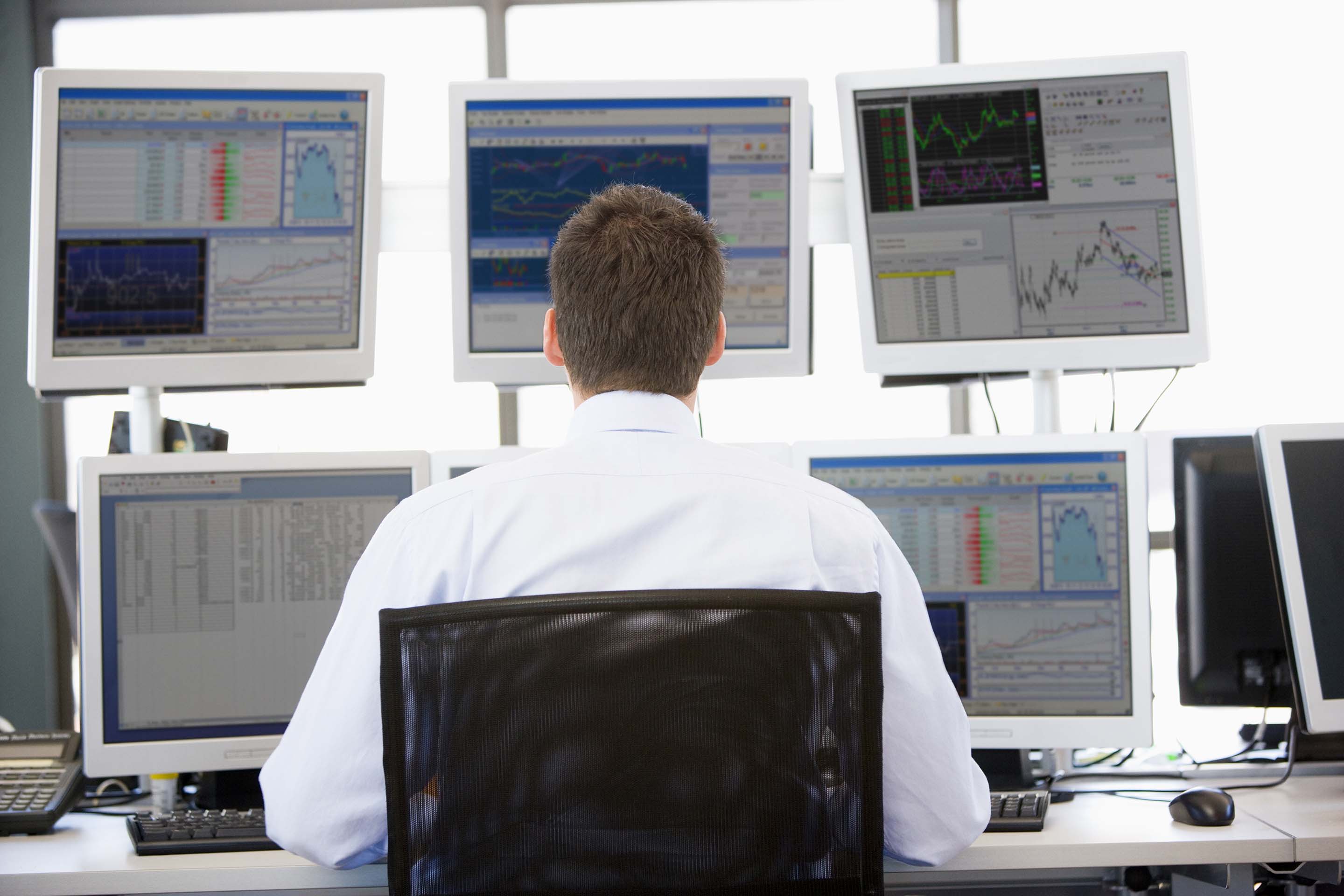Back view of man reviewing analytics on several screens