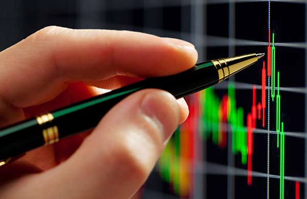 Hand with a pen measuring performance indicators for stock or crypto trading