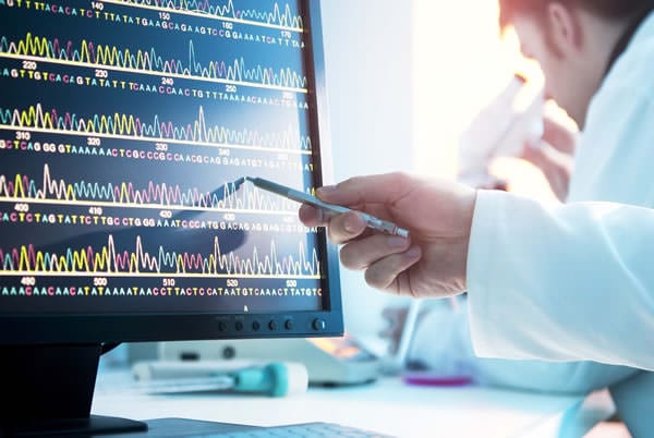 Doctor pointing to DNA analytics on monitor